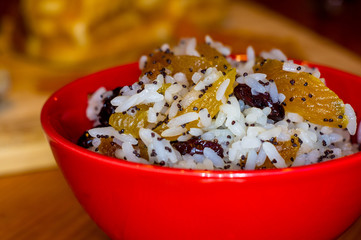 handmade preparation of treats for traditional Orthodox Christmas - rice pudding with fruits, cranberries, honey, nuts, Church candles
