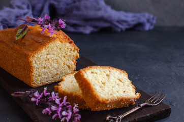 Lemon pound cake on dark stone background with lemon.