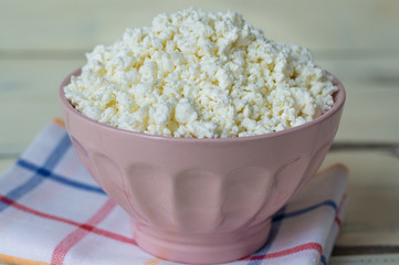 Cottage cheese, tvorog, farmer's cheese in a simple bowl, wooden background