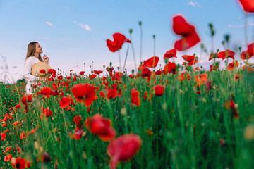 Beautiful woman in a poppy field holding a bouquet of poppies. g
