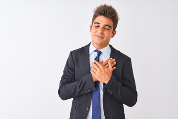 Young handsome businessman wearing suit standing over isolated white background smiling with hands on chest with closed eyes and grateful gesture on face. Health concept.