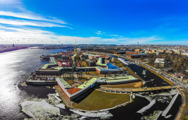 Beautifull aerial view of the Petropavlovsky fortress in sunny winter day. Golden tall spire of famous Peter and Paul Cathedral on the blue sky background. Historical centre of St. Petersburg, Russia.