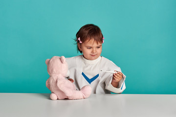 Child girl playing doctor with a teddy bear