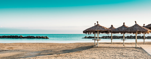 Montesilvano Beach, Italy. Wicker umbrella in sand. Panorama.