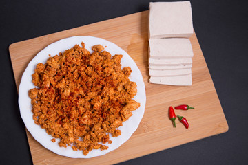 Chorizo vegano hecho con tofu firme, paprika y especias en una tabla de madera sobre fondo negro.