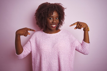 Young african afro woman wearing sweater standing over isolated pink background looking confident...