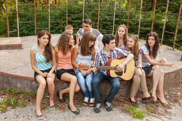 Obraz na płótnie Canvas Cheerful teenagers playing guitar and singing
