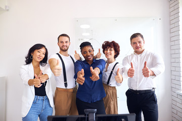 Smiling team portrait of diverse interracial business group standing in office, white background, thumb