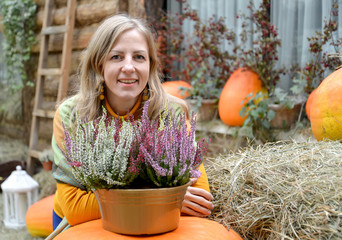 A happy woman with a veil against the background of orange pumpkin in the yard of a rural house....