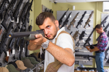 Portrait of young male which is choosing air-powered gun
