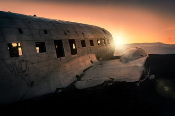 Damaged airplane on mountain against sunset