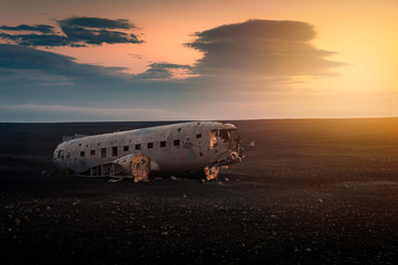 Crushed plane Dakota on black beach at the sunset