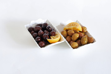 Obraz premium Green and black olives on plate on white background.