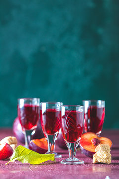 Plums strong alcoholic drink in shots. Hard liquor, slivovica, plum brandy or plum vodka with ripe plums