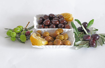 Green and black olives on plate on white background.