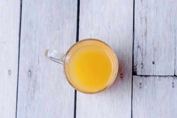 Fototapeta na wymiar Half cup of orange juice on a white wooden background. Copy space