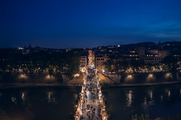 Bridge to Castle of Holy Angel with people at night in Rome historic centre, view from above.