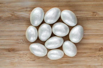 Almonds in white glaze lie in the center on a brown wooden surface, top view