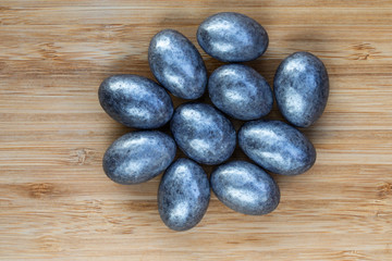 Almonds in silver glaze lie in the center on a brown wooden surface, top view