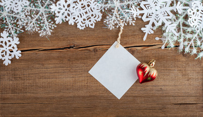 Christmas greeting card with snowflakes and Christmas toy, Empty paper mock up. New Year accessories on wooden background. Christmas celebration concept. Place for text, Flat lay, top view, copy space