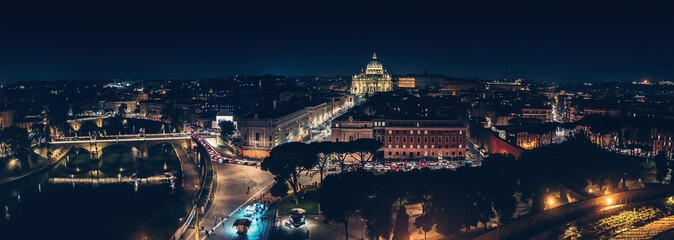 Obraz na płótnie Canvas St Angel Bridge on Tiber river and St. Peter Basilica in Vatican City at night with city illumination in Rome, Italy, view from above, panorama.