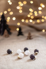 Close up glossy christmas balls with a paper christmas trees and and bokeh light as a background. Copy space