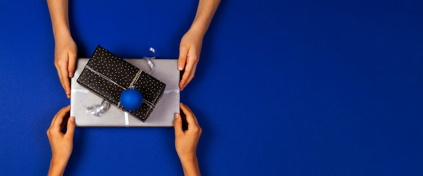 Hands give presents boxes over navy blue background. Christmas, New Year, holidays concept