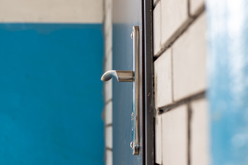 Chrome door handle with lock in a metal door. Side view close-up.