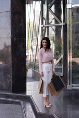Happy young women going out shopping mall after shopping with packages of shop's goods. Shop sales,...