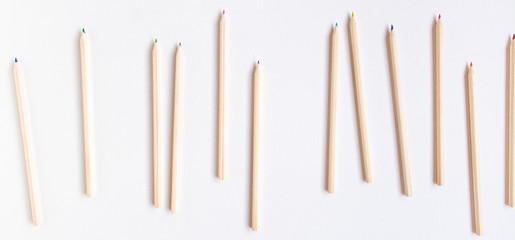 Banner top view flat lay of a group of wooden pencils that roll out of the frame in different directions leaving a blank background. Education concept.