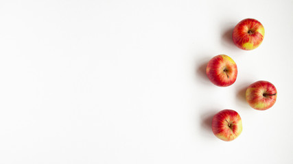  flat lay top view of four red autumn apples that climb to the upper right corner. Food concept with space for text.