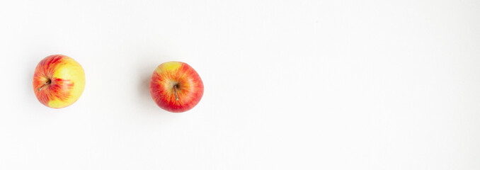 Banner flat lay top view of two red apples of the left side of frame on white background. Still life with space for text