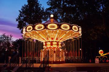 Obraz premium Carousel Merry go round in amusement park at evening city