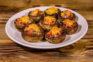 Baked champignons stuffed with minced meat and cheese in plate on a wooden table