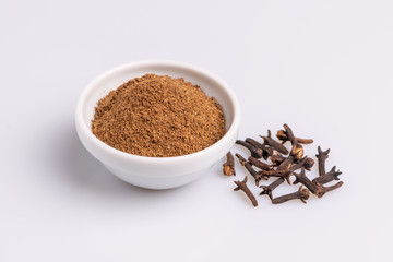 Ground cloves in white ceramic bowl isolated on white background, soft light, studio shot, copy space.Whole cloves.