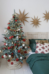 cozy bedroom with a Christmas tree decorated for the new year in red-green tones