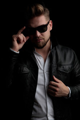 Obraz premium casual man standing and fixing his sunglasses and jacket