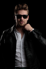 Obraz premium casual man wearing sunglasses standing and fixing his collar