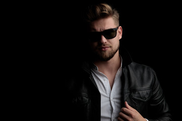 Obraz premium casual man wearing sunglasses standing and arranging jacket
