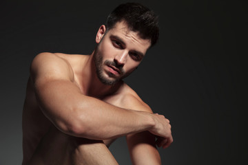 dramatic naked guy holding arm on knee