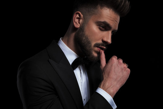 businessman wearing black tuxedo seductively touching lips