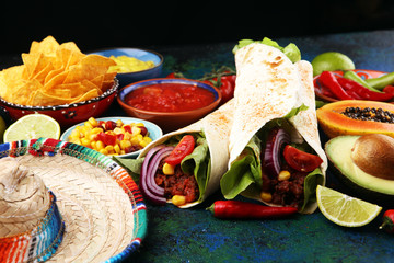 Mexican food, including tacos, guacamole, nachos and pepper on rustic table