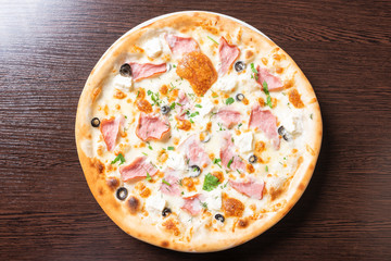 Cheap pizza with curd cheese, ham, olives, and herbs.
