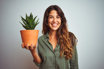 Young beautiful woman holding cactus pot over white isolated background with a happy face standing...