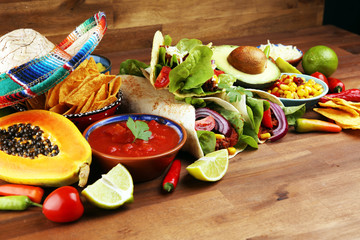 Mexican food, including tacos, guacamole, nachos and pepper on rustic table
