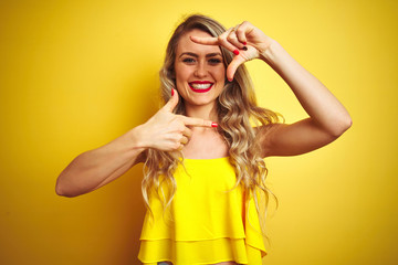 Young attactive woman wearing t-shirt standing over yellow isolated background smiling making frame with hands and fingers with happy face. Creativity and photography concept.