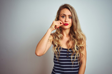 Young beautiful woman wearing stripes t-shirt standing over white isolated background mouth and...