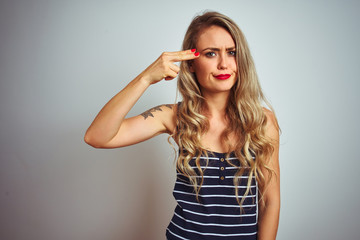 Young beautiful woman wearing stripes t-shirt standing over white isolated background Shooting and killing oneself pointing hand and fingers to head like gun, suicide gesture.