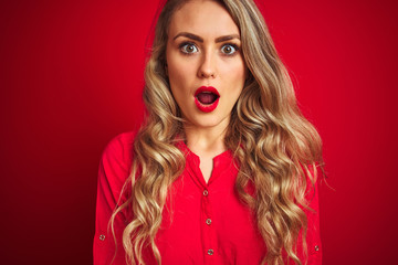 Young beautiful woman standing over red isolated background scared in shock with a surprise face, afraid and excited with fear expression