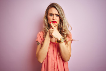 Young beautiful woman wearing t-shirt standing over pink isolated background Rejection expression crossing fingers doing negative sign